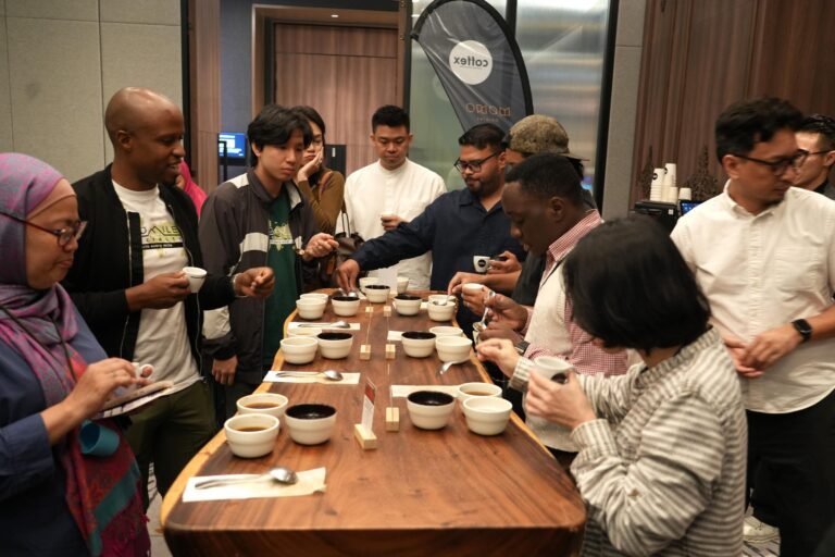 A full cupping table surrounded by roasters, café owners and buyers tasting Ugandan coffee