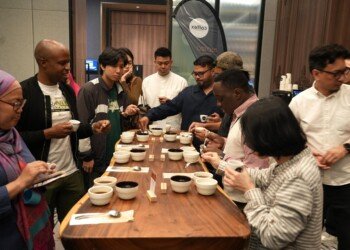 A full cupping table surrounded by roasters, café owners and buyers tasting Ugandan coffee