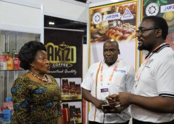 Uganda High Commission and exhibitor team in conversation at the Uganda stand, beside Akizi Coffee branding and a display of Jesa dairy, juice and honey products