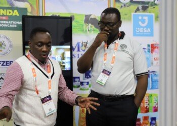 A Uganda Halal Bureau representative speaking with a trade buyer in front of Jesa dairy and juice displays at the Uganda stand